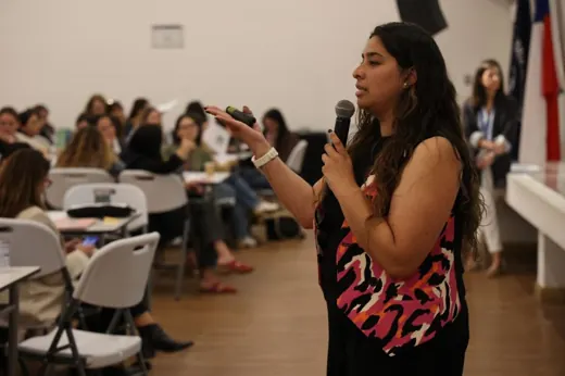 Cote habla con un micrófono frente a un grupo de profesoras en un taller